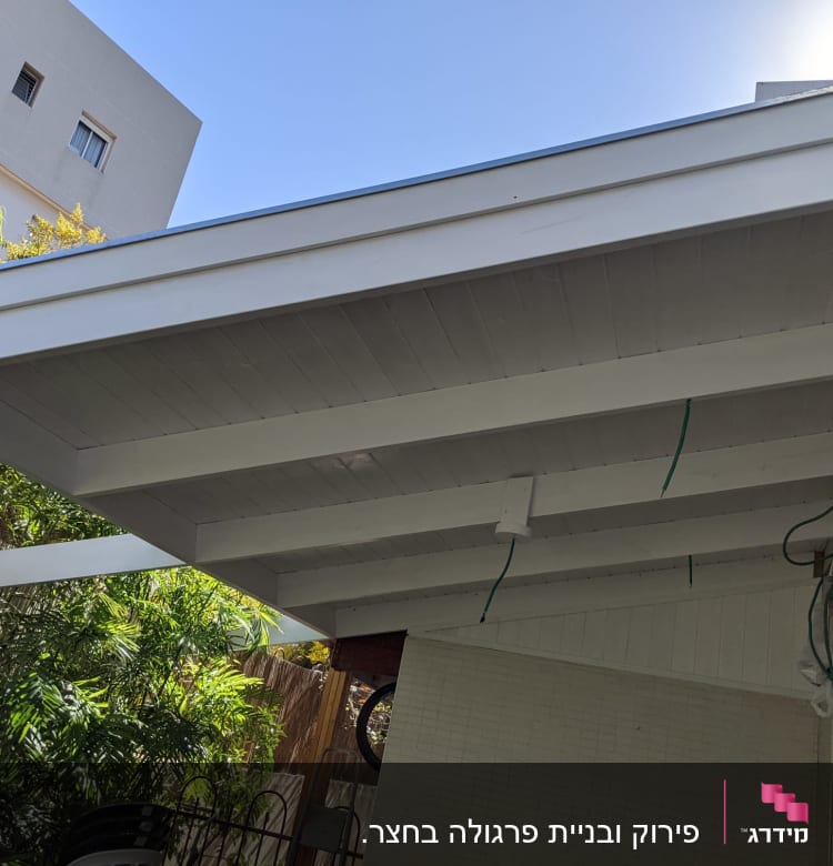 גג עץ לבן עם קורות חשופות וחוטים ירוקים תלויים
